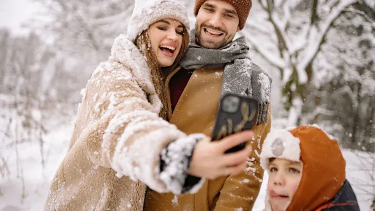 Foreldre og barn tar selfie med mobilen i snøvær